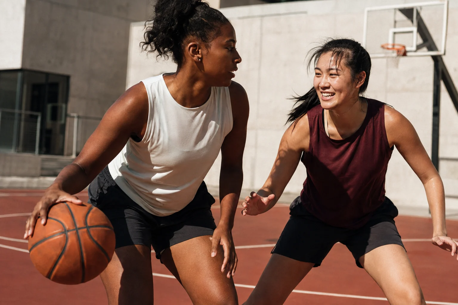 Two women sharing a friendly game on an outdoor basketball court