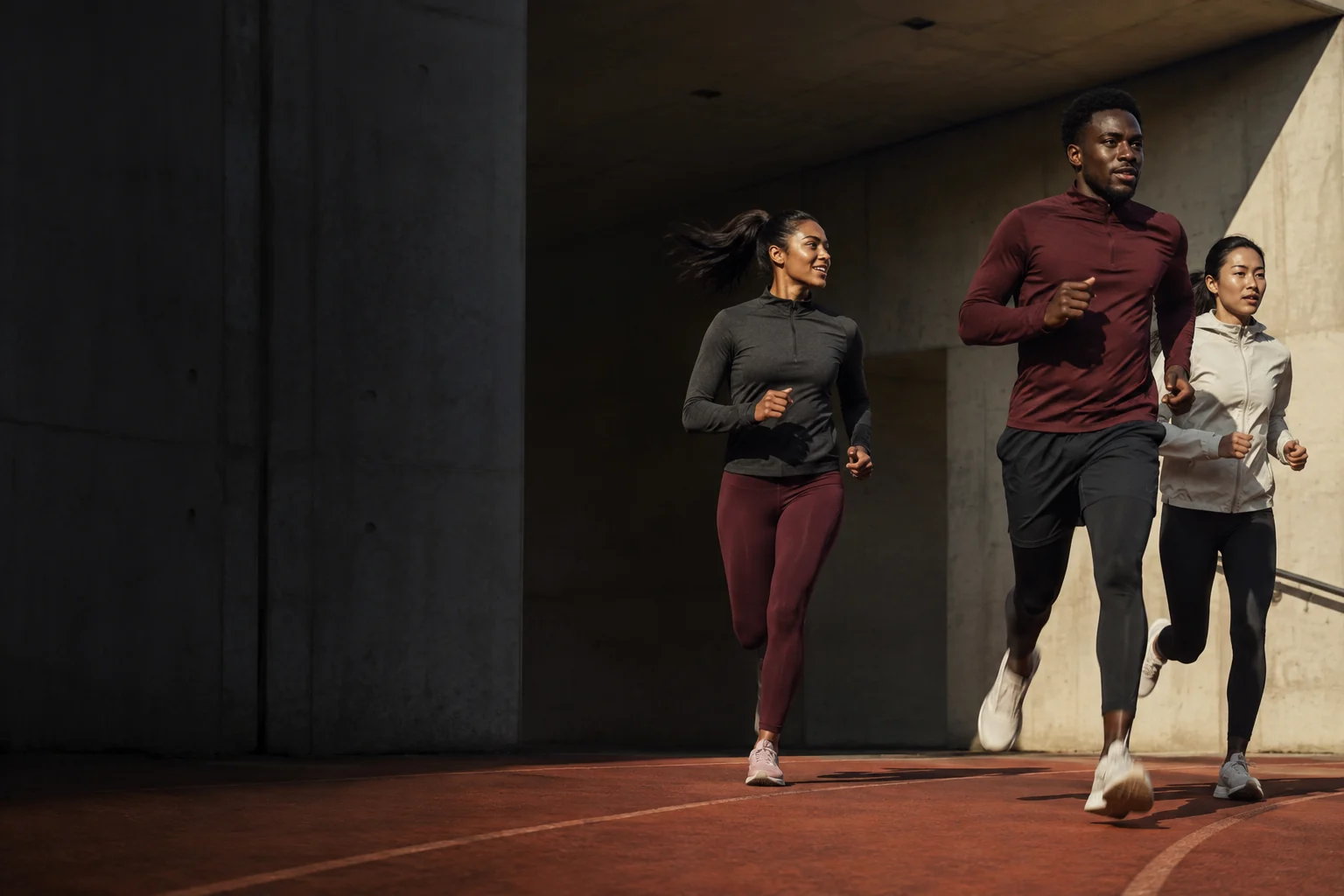 Three friends running together through a sunlit sports pavilion